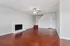 Bright and spacious living room featuring elegant wood-style flooring, a cozy white brick fireplace, and a modern ceiling fan.