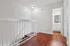 Bright hallway with elegant wood-style flooring leading to a modern bathroom, featuring sleek white cabinetry and chic lighting.
