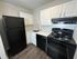 Modern kitchen with sleek black appliances, elegant white cabinetry, and a glossy quartz countertop, offering a blend of style and functionality.