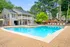 Inviting poolside view featuring a modern clubhouse, surrounded by lush greenery and elegant lounge chairs, perfect for relaxation and social gatherings.