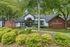 Inviting apartment community entrance at Rosemont Brookhollow, featuring lush green landscaping, modern architecture, and a welcoming pathway.