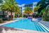Luxurious apartment complex with a stunning pool area, surrounded by palm trees and elegant architecture, creating a tropical oasis for residents.