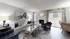 Bright and inviting living room with elegant decor, featuring a cozy gray sofa, stylish chairs, and a modern fireplace, all bathed in natural light from large windows overlooking a serene outdoor view.
