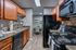 Modern kitchen with sleek black appliances, warm wooden cabinetry, and elegant countertops, leading to a cozy dining area.