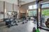 Bright and modern fitness center featuring state-of-the-art exercise bikes, treadmills, and an array of weight machines, all set against large windows with a scenic view.