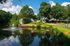 Peaceful lakeside view showcasing beautiful homes surrounded by lush greenery and a sparkling fountain, perfect for serene living.