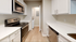 Contemporary kitchen with sleek white cabinetry, stainless steel appliances, and elegant wood flooring.