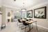 Elegant dining area with modern decor, featuring a wooden table set for four, large floral artwork, and sunlight streaming through large windows.