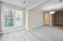 Bright and inviting apartment interior showcasing large window views, elegant lighting, and a seamless transition from hardwood to carpeted flooring.