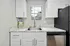 Modern kitchen with sleek marble countertops, white cabinetry, stainless steel sink, and natural light through a charming window.