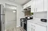 Modern kitchen with sleek white cabinets, marble countertops, and stainless steel appliances leading to an inviting dining area.