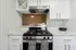 Chic modern kitchen with sleek marble countertops, stylish white cabinetry, and a stainless steel gas stove accented by elegant decor.