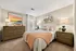 Charming bedroom featuring a cozy bed with stylish cushions, modern wooden dressers, and vibrant wall art, illuminated by soft lighting for a warm ambiance.