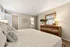 Inviting bedroom with cozy decor, plush pillows, elegant dresser, and soft lighting, creating a serene atmosphere.