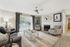 Inviting living room with modern decor, featuring a cozy grey sofa, stylish patterned chairs, and a chic glass coffee table. Natural light floods in through expansive windows, enhancing the elegant fireplace and contemporary wall art.