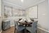Elegant dining area with a round wooden table set for four, featuring modern artwork and stylish decor against a neutral backdrop.