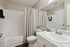 Modern bathroom with elegant white fixtures, a cozy bathtub, chic marble countertop, and stylish decor accents.