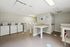 Bright and spacious communal laundry room with multiple washers, dryers, and practical folding tables, offering convenience and ease for residents.