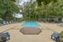 Inviting outdoor pool area with sun loungers, surrounded by lush greenery and shaded seating, perfect for relaxation.