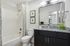 Modern bathroom with sleek granite countertop, elegant lighting, and decorative accents, featuring a stylish shower with a patterned curtain.