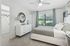 Bright and inviting bedroom with modern decor, featuring a comfortable bed, stylish dresser, and large window with scenic view.