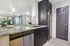 Modern kitchen with sleek granite countertops, stainless steel appliances, and open layout leading to a bright living area with artistic decor.
