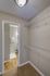 Chic and cozy apartment walk-in closet with wire shelving, leading into a bright bathroom with elegant wood flooring.
