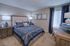 Elegant bedroom with a plush queen bed, adorned with blue paisley bedding and chic decor, featuring ambient lighting and framed artwork for a cozy atmosphere.