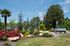 Beautifully landscaped entrance to Rosemont Peachtree Corners, featuring lush greenery, vibrant flowers, and flags under a clear blue sky.