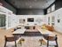 Modern and inviting living space featuring a sleek black ceiling, comfortable seating, vibrant decor, and abundant natural light through large windows.