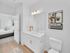 Elegant and bright bathroom with modern fixtures, adjacent to a cozy bedroom, featuring sleek white cabinetry and stylish decor accents.