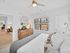 Bright, modern bedroom with plush bedding, wooden dresser, and elegant decor featuring a large window offering natural light.