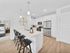 Bright and modern kitchen with sleek white cabinetry, stainless steel appliances, and a stylish breakfast bar with pendant lighting, adjacent to a cozy bedroom.