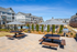 Inviting residential community showcasing outdoor dining area with picnic tables and umbrellas, adjacent to a pristine swimming pool and modern apartment buildings.