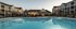 Elegant apartment complex with modern architecture surrounding a sparkling blue swimming pool, perfect for relaxation and leisure.