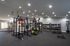 Modern fitness center with state-of-the-art equipment, including squat racks, weights, and kettlebells, offering a bright and spacious workout environment.