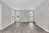 Bright living room with elegant wood flooring and large windows inviting natural light and greenery.