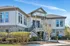 Charming apartment building exterior with stone accents, large windows, and inviting entryway surrounded by well-maintained greenery.