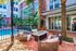 Chic outdoor patio with cozy seating and a modern fire pit, overlooking a refreshing pool, surrounded by lush greenery and contemporary architecture.