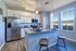 Bright and modern kitchen with sleek stainless steel appliances, elegant white cabinets, and a chic breakfast bar with wooden stools.