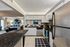 Modern open-plan kitchen with sleek stainless steel appliances and a cozy, elegantly furnished living area in the background.