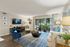 Luxurious living room with elegant decor, featuring a plush blue armchair, modern furnishings, and a scenic view through large glass doors.