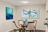 Chic dining area with modern abstract art, featuring a glass table and elegant wood chairs in a stylish apartment setting.