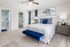 Inviting bedroom with elegant decor, featuring a plush bed with vibrant blue accents, stylish artwork, and a cozy seating area near a spacious walk-in closet and modern en-suite bathroom.