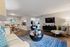 Inviting living room with modern decor, featuring plush seating, stylish coffee table, elegant dining area, and a wall-mounted TV.