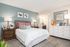 Inviting bedroom with modern decor, featuring a cozy bed, stylish wooden nightstand, and chic dresser, accented by contemporary artwork.