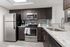 Modern kitchen with sleek stainless steel appliances, dark wood cabinets, and elegant granite countertops under bright lighting.