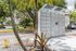 Modern parcel locker under sleek glass canopy amidst lush tropical landscaping, perfect for convenient package management.