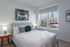 Bright and modern bedroom featuring a plush bed with elegant decor, large window with city views, and stylish artwork on the walls.