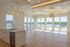 Elegant open-concept living space with large windows showcasing stunning city views, featuring modern lighting and a sleek kitchen island.